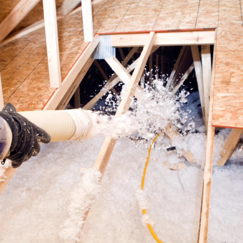a person blowing insulation fibers in the attic